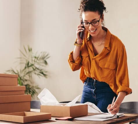 Young Black or Hispanic woman on the phone and writing down personal credit score