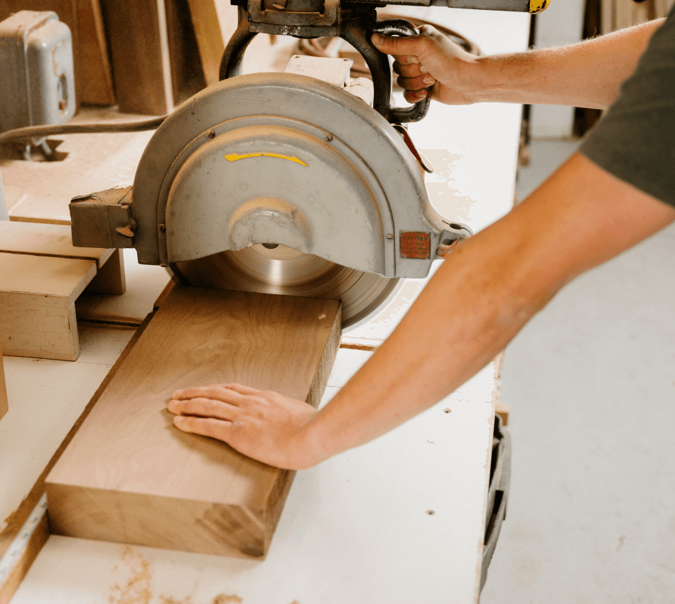 Close-up of a construction worker cutting a piece of wood with a circular saw.