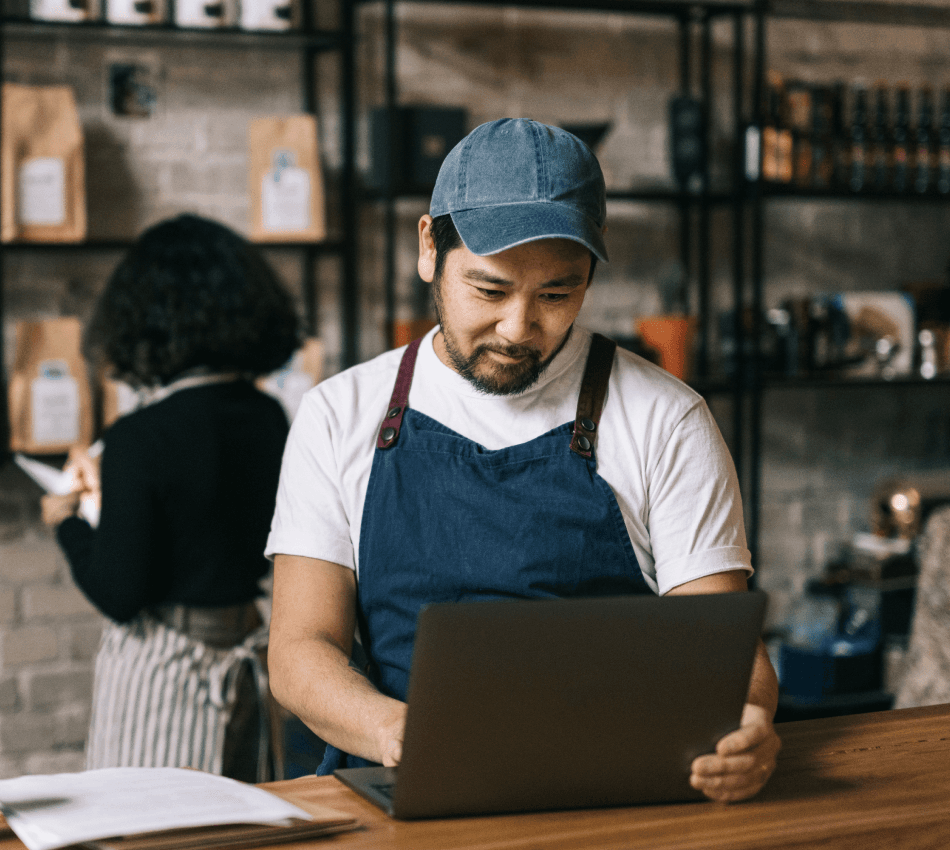 Small business owner manages business finances on a laptop from the counter of their coffee shop.