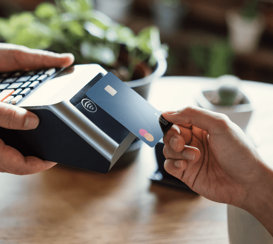 A woman holding a credit card while she looks at her laptop screen and smiles.